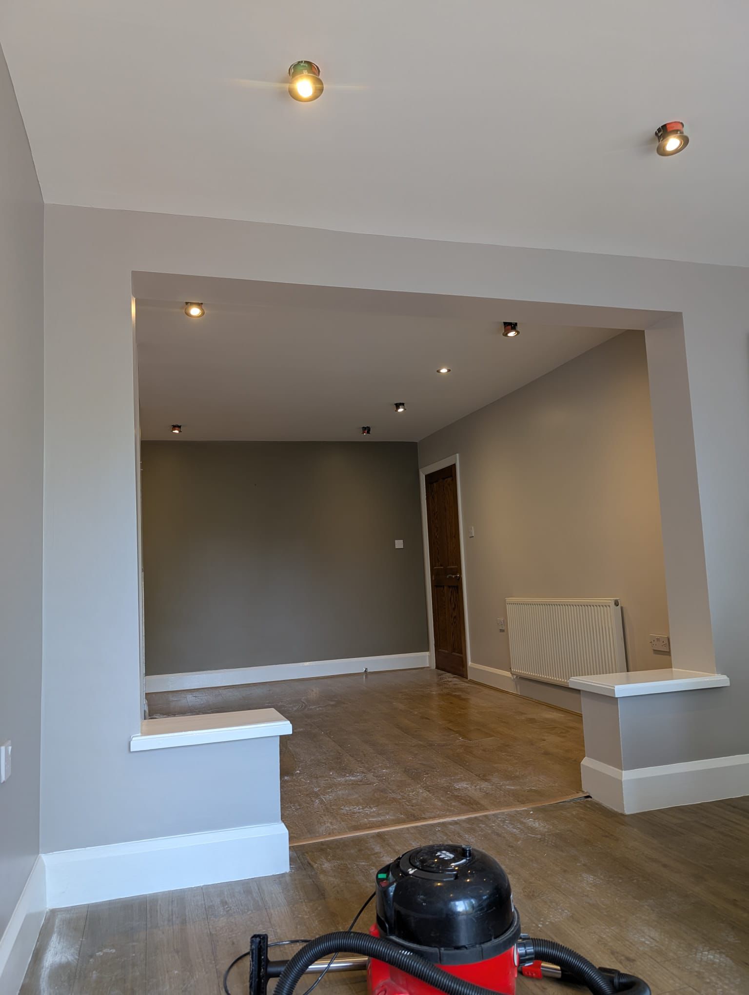 Open-plan living room with professionally painted grey feature wall and archway